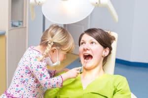Kid is checking her mother's teeth